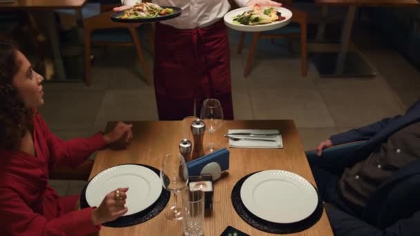 Camarero sirviendo comida de restaurante a pareja multiétnica en una cena romántica. - Metraje, vídeo