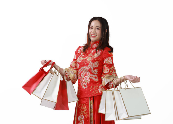 Cheerful Asian shopaholic woman wearing traditional cheongsam qipao dress holding shopping bag, Happy Chinese new year  - Foto, immagini