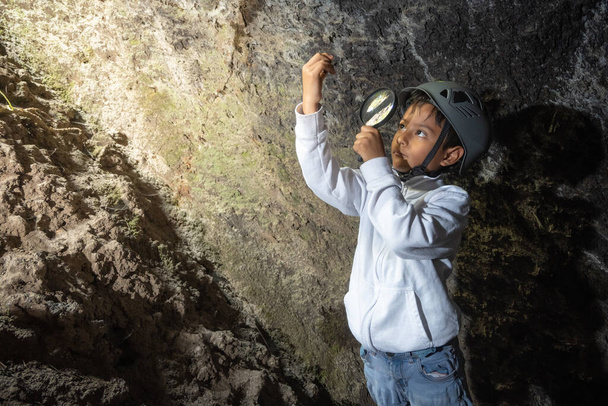 Junge erkundet und beobachtet Felsen in einer Höhle - Foto, Bild