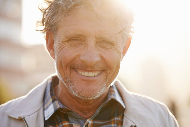 Napfényes kilátásai vannak az életre. Egy barátságos kinézetű középkorú férfi portréja odakint.. - Fotó, kép