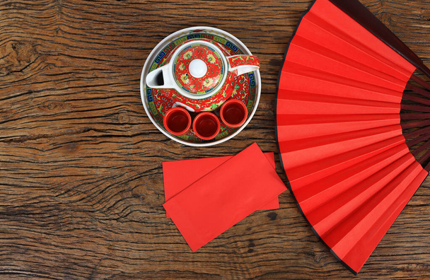 Chinese culture and lifestyle concept. Horizontal background  of  Chinese new year day, Red envelope and hot tea set decor with red fan on wooden floor - Фото, изображение