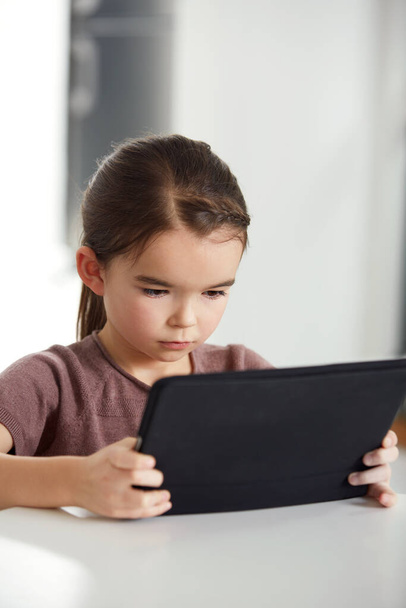 Betrokken bij haar digitale media. Opname van een schattig klein meisje dat een digitale tablet leest. - Foto, afbeelding