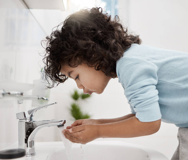 Temiz ve taze kalmak. Evdeki bir banyoda ellerini ve ağzını yıkayan sevimli bir çocuğun fotoğrafı.. - Fotoğraf, Görsel