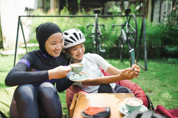 beautiful cyclist take a break at coffee shop and taking photos together - 写真・画像