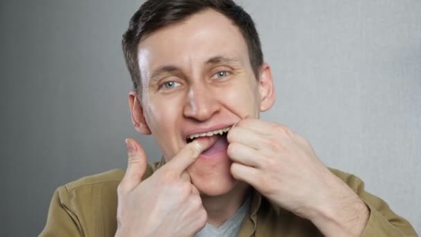 Blisko młody człowiek nici dentystycznej zębów z nici dentystycznej - Materiał filmowy, wideo