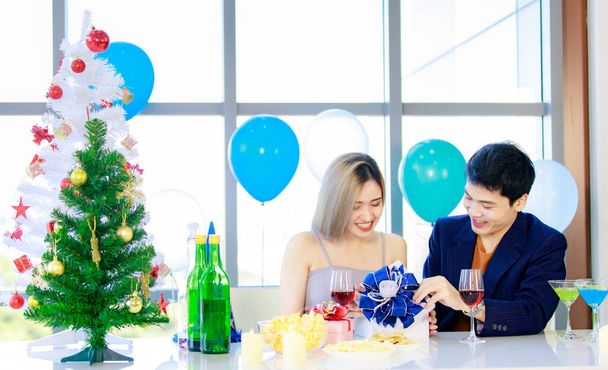 Millennial giovane coppia di innamorati marito asiatico in abito formale e bella moglie sorridente tenendo bicchieri alti vino brindare applausi insieme in felice festa di Capodanno a tavola decorata bevanda e cibo. - Foto, immagini