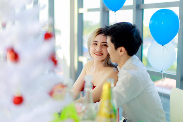 Millennial νεαρός Ασιάτης εραστής ζευγάρι όμορφος φίλος και όμορφη φίλη στο κόκκινο φόρεμα κάθεται χαμογελώντας στο τραπέζι στο εστιατόριο, ενώ αρσενικό μαζί γιορτάζει χρονολόγηση επέτειο. - Φωτογραφία, εικόνα