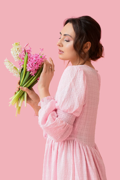 Красива молода жінка з квітами гіацинта на рожевому фоні
 - Фото, зображення