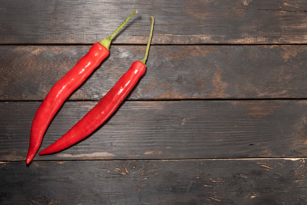 Rode peper chili geïsoleerd op donkere houten achtergrond close-up, bovenaanzicht, voedselconcept. - Foto, afbeelding