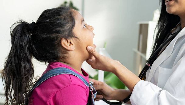 маленька дівчинка в кабінеті лікаря хворіє, лікар дивиться на її рот
 - Фото, зображення