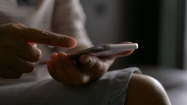 Mujer en vestido casual usando la pantalla táctil de su teléfono inteligente móvil desplazable por los dedos en la aplicación de comunicación en línea social con Internet inalámbrico para el hogar. Aislamiento doméstico con dispositivo digital. - Metraje, vídeo