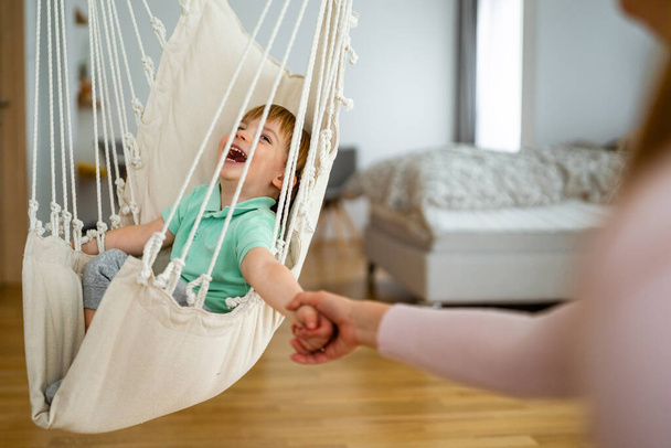 Beautiful woman and her little son having fun, playing at home. Happy family concept - 写真・画像