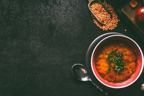Red lentil soup with spoon in bowl on dark rustic background , top view with copy space. Vegan and vegetarian food - Foto, Imagem