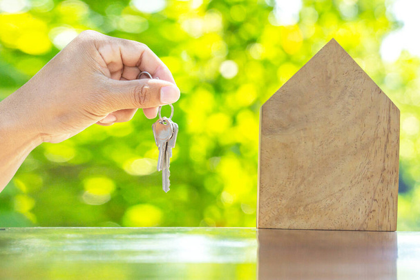 Close up holding house key in hand.Mortgage loan approval home loan and insurance concept.on green natural background. - Photo, Image