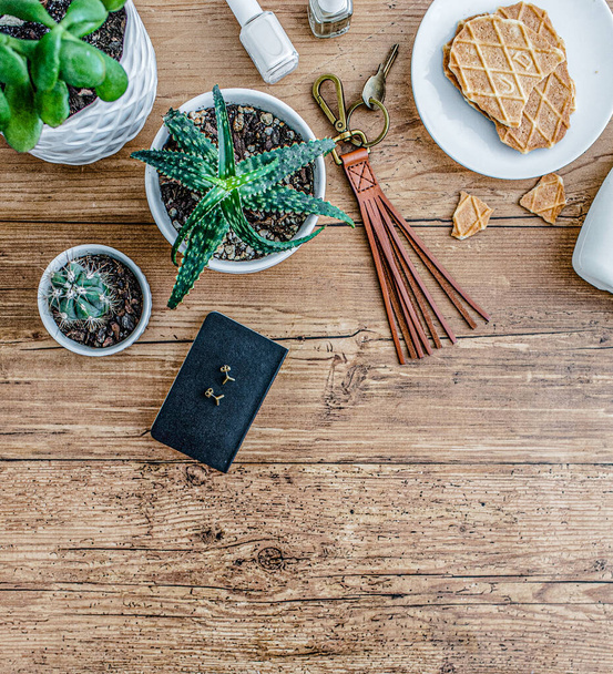 There are green plants and a waffle on a white saucer on the wooden table top. - Photo, Image