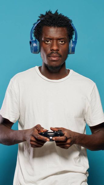 Νεαρός που κρατάει χειριστήριο για να παίξει βιντεοπαιχνίδια στην κονσόλα - Φωτογραφία, εικόνα