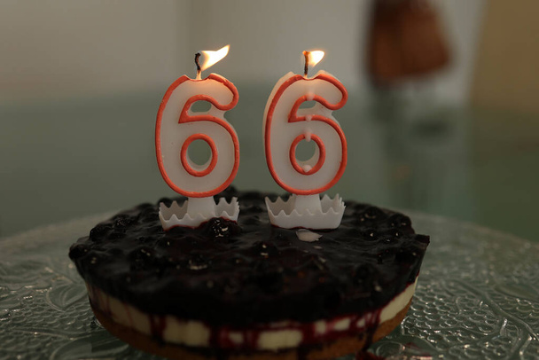 Birthday cake. Birthday cake with burning candle number 66. - Fotoğraf, Görsel