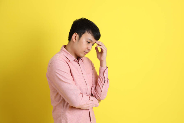 L'homme asiatique avec chemise rose debout sur le fond jaune. - Photo, image