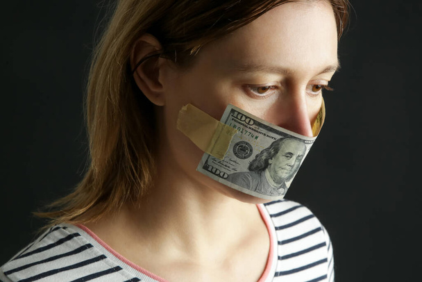Geld erkauft Schweigen. Frauenmund mit Dollarschein bedeckt. Konzept für Korruption und Meinungsfreiheit. - Foto, Bild