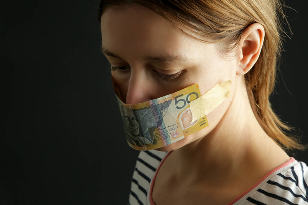 Гроші купують тишу. Рот жінки покритий австралійським доларом. Корупція і свобода слова. - Фото, зображення