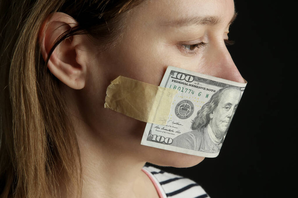 L'argent achète le silence. La bouche d'une femme couverte d'un billet de dollar. Concept de corruption et de liberté d'expression. - Photo, image