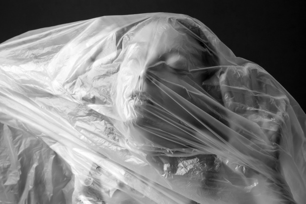 Woman wrapped in plastic sheet. Studio shot. Woman and mental health concept. - Fotó, kép