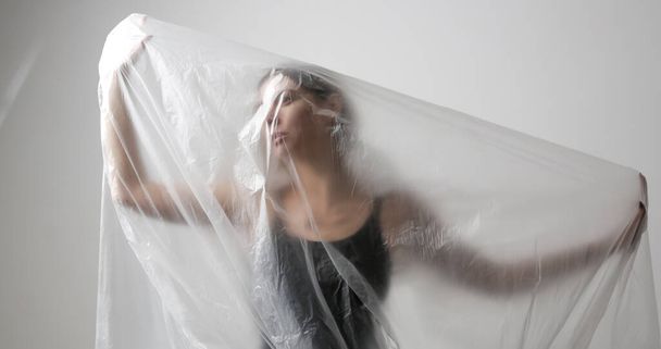 Mulher embrulhada em folha de plástico. Tiro no estúdio. Conceito de mulher e saúde mental. - Foto, Imagem