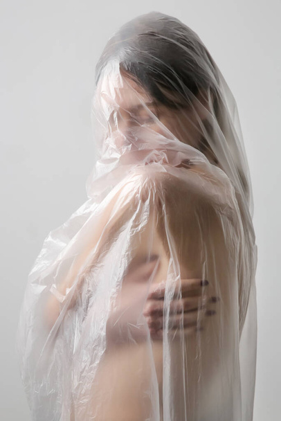 Mujer envuelta en lámina de plástico. Grabado en estudio. Concepto de mujer y salud mental. - Foto, imagen