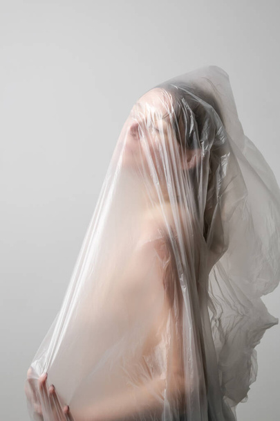 Mulher embrulhada em folha de plástico. Tiro no estúdio. Conceito de mulher e saúde mental. - Foto, Imagem