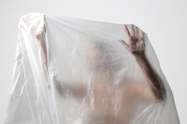 Woman wrapped in plastic sheet. Studio shot. Woman and mental health concept. - Foto, afbeelding