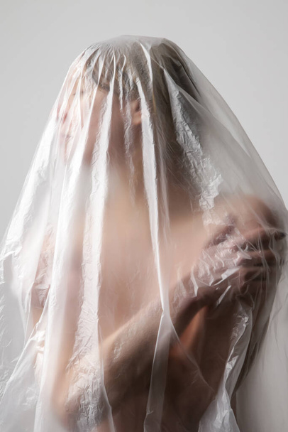 Woman wrapped in plastic sheet. Studio shot. Woman and mental health concept. - Valokuva, kuva