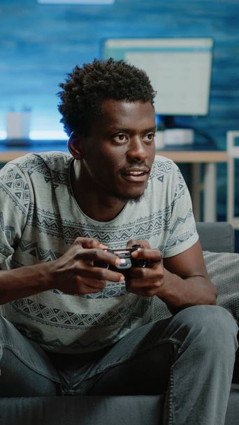 Jong volwassene verliest bij videospelletjes op TV console met joystick - Foto, afbeelding
