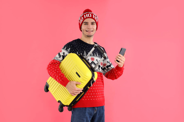 Guy in Christmas pulóver bőrönddel rózsaszín háttér - Fotó, kép