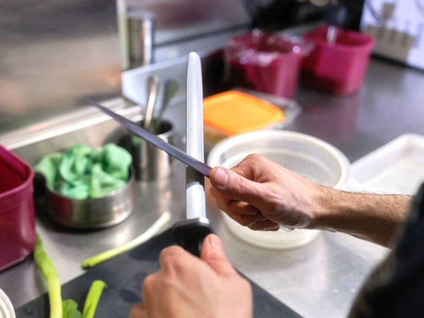 Cook sharpening kitchen knives in a restaurant - Photo, Image