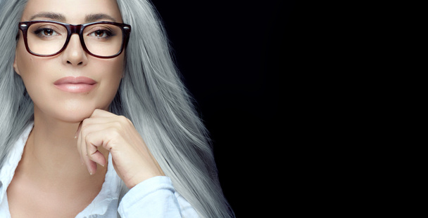Occhiali da donna. Elegante donna capelli d'argento in occhiali chiari fissando la fotocamera con fiducia in se stessa. Bandiera panoramica isolata su nero con spazio di copia - Foto, immagini