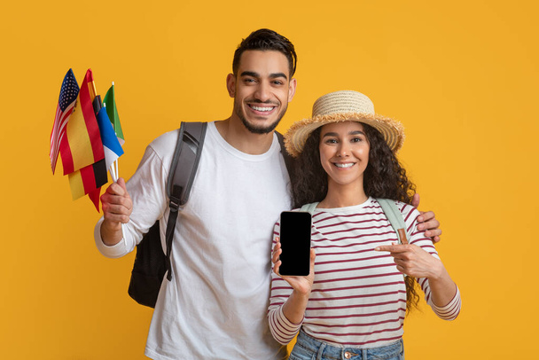 Online-Übersetzer-App Glückliches junges Paar mit internationalen Fahnen und leerem Smartphone - Foto, Bild