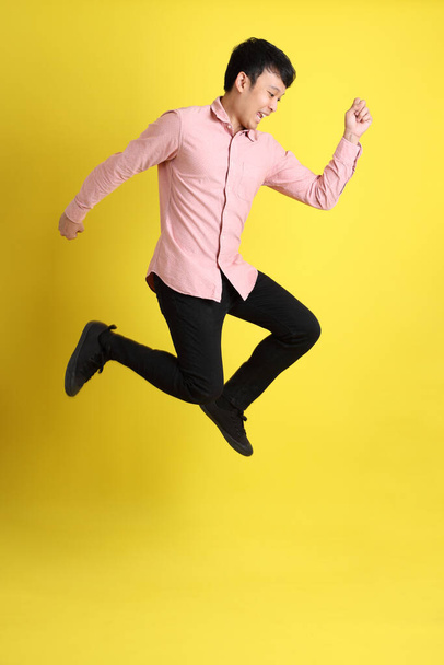 The Asian man with pink shirt standing on the yellow background. - Foto, Imagen