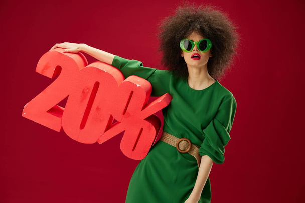 Positive young woman green dress afro hairstyle dark glasses twenty percent in hands studio model unaltered - Photo, Image