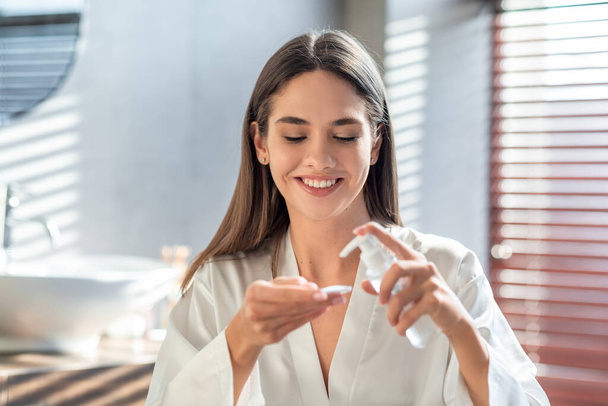 幸せな若い女性は、洗顔のために綿パッドに親水性油を適用します顔 - 写真・画像