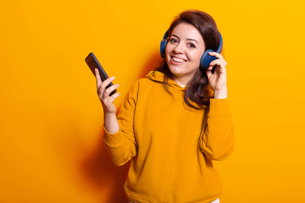 Portrait of positive woman using headphones and phone - Zdjęcie, obraz