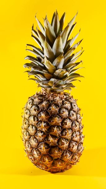 Beautiful fresh pineapple isolated on yellow background. Summer seasonal fruit design idea pattern concept. Copy space, close up - Foto, Imagen