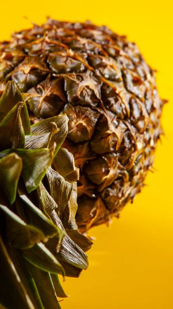 Beautiful fresh pineapple isolated on yellow background. Summer seasonal fruit design idea pattern concept. Copy space, close up - 写真・画像