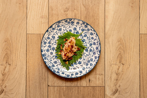 кусок жареной курицы с ветчиной тако на зеленом листе шисо и украшенной фарфоровой тарелкой - Фото, изображение