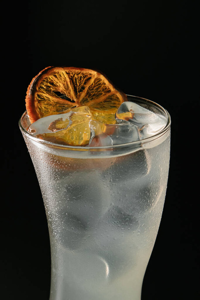 glass of water with lemon and ice cubes on black background - Foto, Imagen