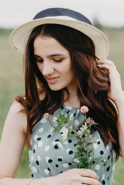 portrait of a young girl in a straw hat in a summer green field - Fotografie, Obrázek