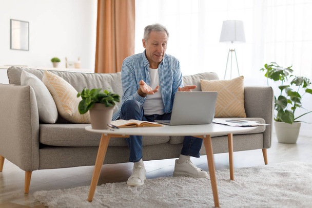 Mature man having video call using laptop and talking - Foto, Bild
