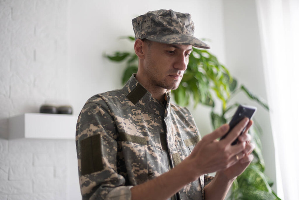 militaire man met telefoon, cyber politie, informatie oorlog - Foto, afbeelding