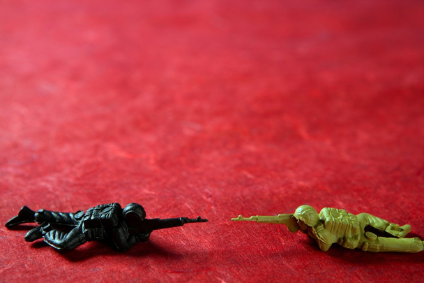 Two plastic toy soldier over red - 写真・画像