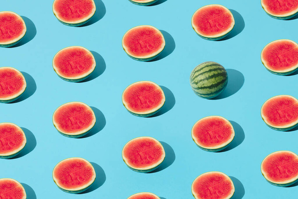 Arranged half watermelon and one whole on a blue pastel background. Minimal pattern and design. - Φωτογραφία, εικόνα