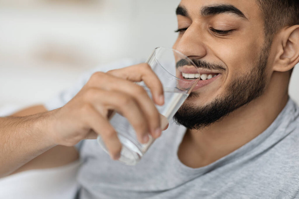 Retrato de joven árabe guapo bebiendo agua de vidrio - Foto, imagen